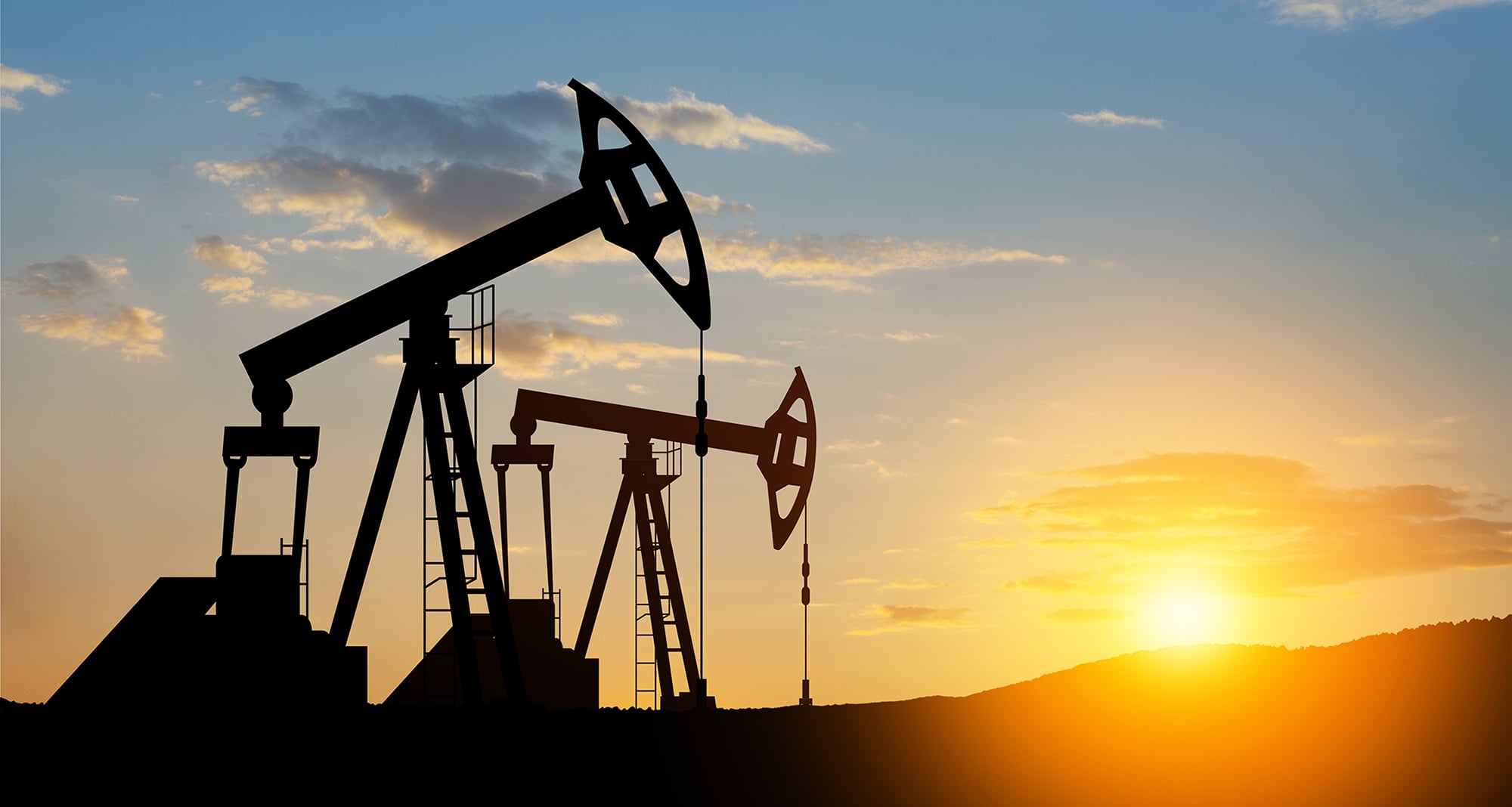 large oil derricks pictured in front of falling horizon